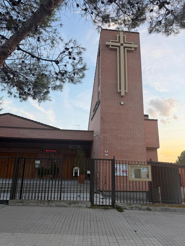 Torre de ladrillo de la parroquia con la gran cruz, al atardecer